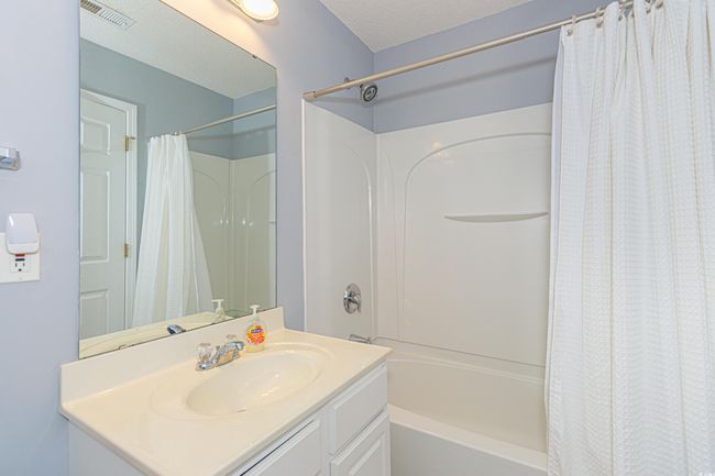 Bathroom featuring shower / bath combo with shower curtain, vanity, and a textured ceiling | Image 24