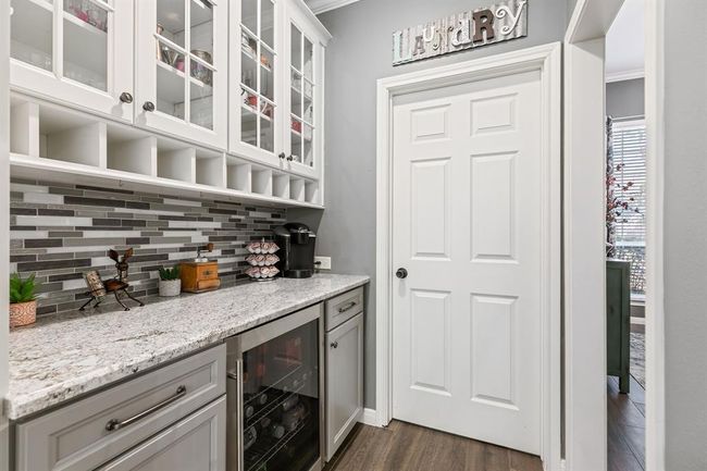 The granite kitchen is a chef's delight, showcasing a stylish tile back-splash & modern appliances, including butlers pantry and beverage cooler. | Image 21