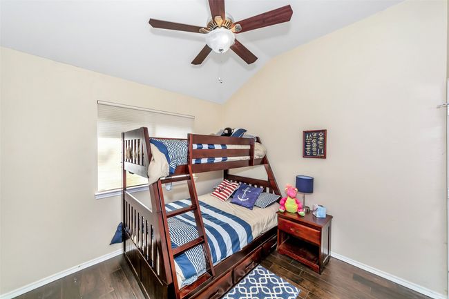 Bedroom with baseboards, wood finished floors, vaulted ceiling, and a ceiling fan | Image 16