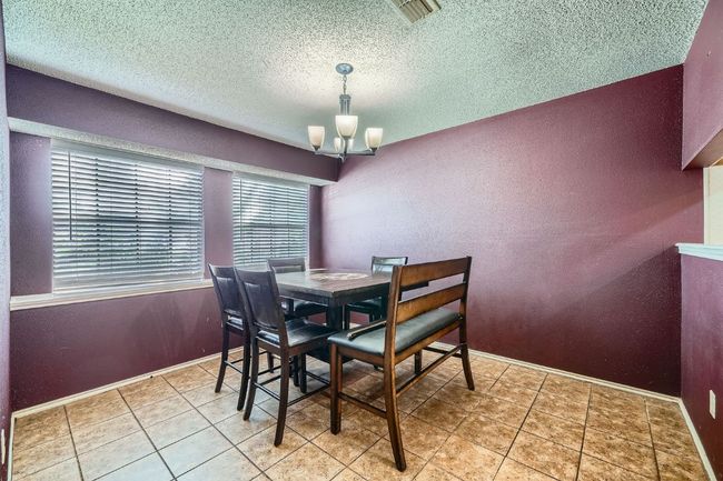 Tiled dining space featuring a chandelier, a textured ceiling, and a textured wall | Image 8