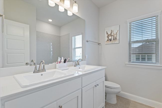 Full bathroom featuring tile patterned floors, toilet, baseboards, double vanity, and a shower | Image 31