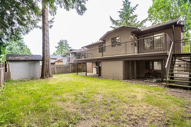 Back of house featuring stairs, a fenced backyard, a deck, and a storage shed | Image 36