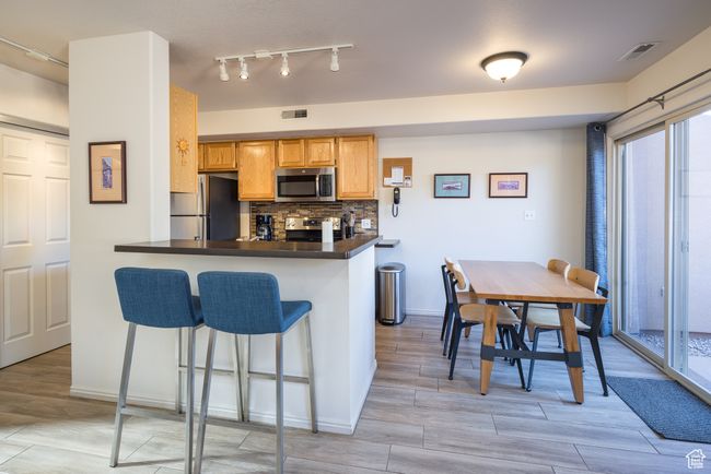 Kitchen with backsplash, kitchen peninsula, a breakfast bar, and appliances with stainless steel finishes | Image 14