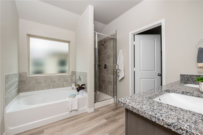 Full bath featuring a stall shower, vanity, a garden tub, and wood finished floors | Image 13