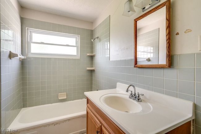 Full bathroom with tile walls, vanity, shower / washtub combination, and a textured ceiling | Image 23