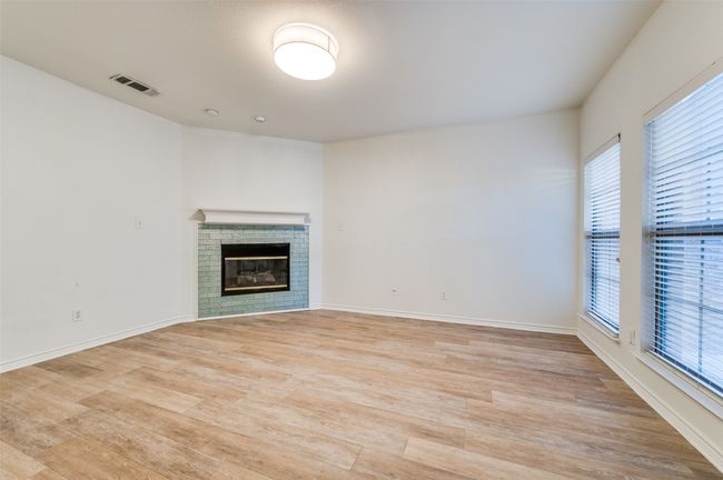 Unfurnished living room with healthy amount of natural light, light wood-type flooring, and a fireplace | Image 5