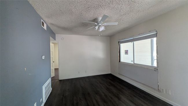 Spare room with dark wood-type flooring, a textured ceiling, and a ceiling fan | Image 7
