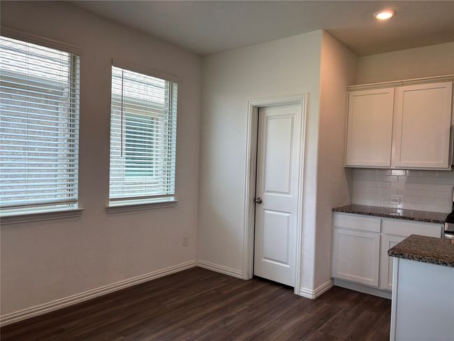 Kitchen featuring dark wood-style flooring, backsplash, white cabinetry, baseboards, and recessed lighting | Image 6