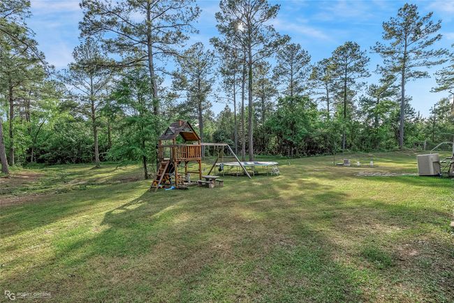 View of yard featuring central AC, a trampoline, and a playground | Image 4