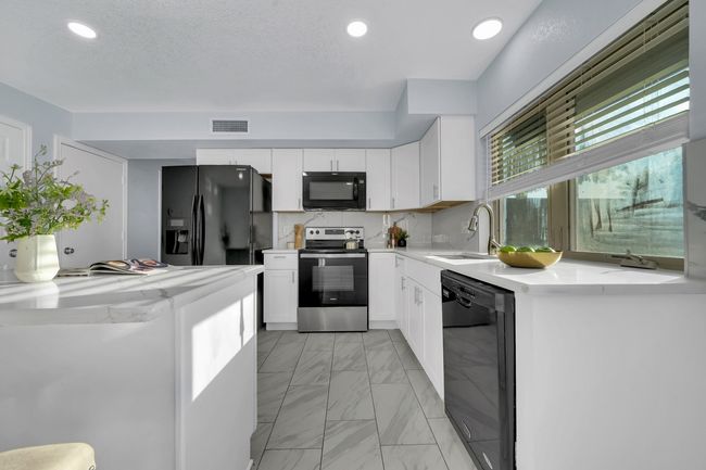Kitchen featuring black appliances, light marble finish floors, white cabinetry, and recessed lighting | Image 28
