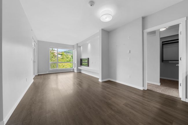 Unfurnished living room featuring dark wood finished floors, baseboards, and a baseboard heating unit | Image 20