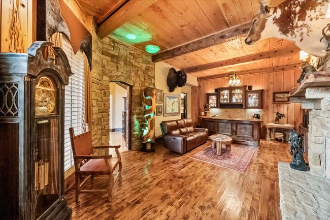 Living area with wood flooring, pecky cypress ceiling, walls, exposed beams and arched walkways | Image 18