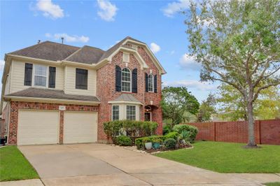 A SPACIOUS DRIVEWAY LEADS TO A TWO-CAR GARAGE, COMPLEMENTED BY MATURE TREES AND A FULLY FENCED BACKYARD FOR PRIVACY. | Image 2