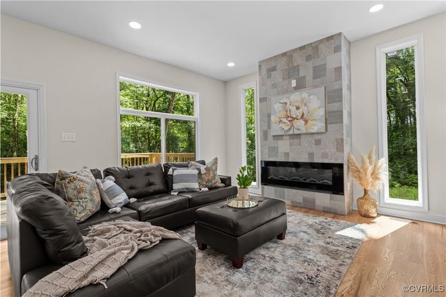 Living room with wood finished floors, recessed lighting, and a tile fireplace | Image 16