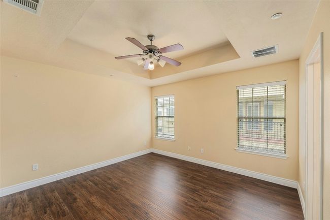 Unfurnished room with a raised ceiling, a ceiling fan, and dark wood-type flooring | Image 13