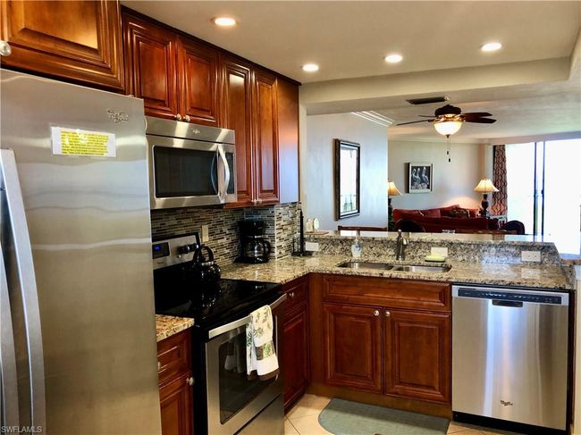 Kitchen with light stone counters, decorative backsplash, appliances with stainless steel finishes, and a sink | Image 6