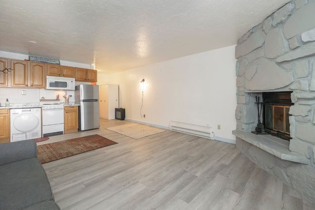 Unfurnished living room featuring a baseboard radiator, light wood-style flooring, and a fireplace | Image 15