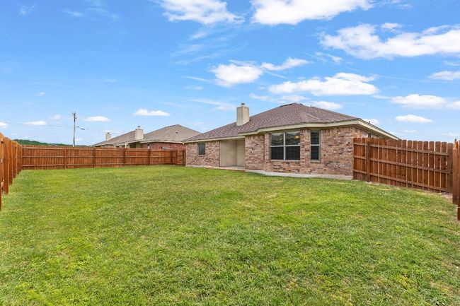 Rear view of property featuring brick siding, a fenced backyard, a chimney, and a shingled roof | Image 35