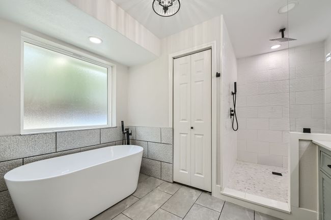 Bathroom featuring a tile shower, a wainscoted wall, a freestanding bath, and tile walls | Image 19
