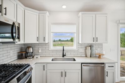 (Photo of a decorated model, actual homes finishes will vary) This spacious kitchen features a large center island, LVP floors, stainless appliances and more. | Image 2