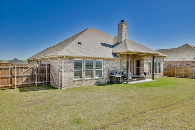 Rear view of house with a patio area, a fenced backyard, brick siding, and a chimney | Image 31