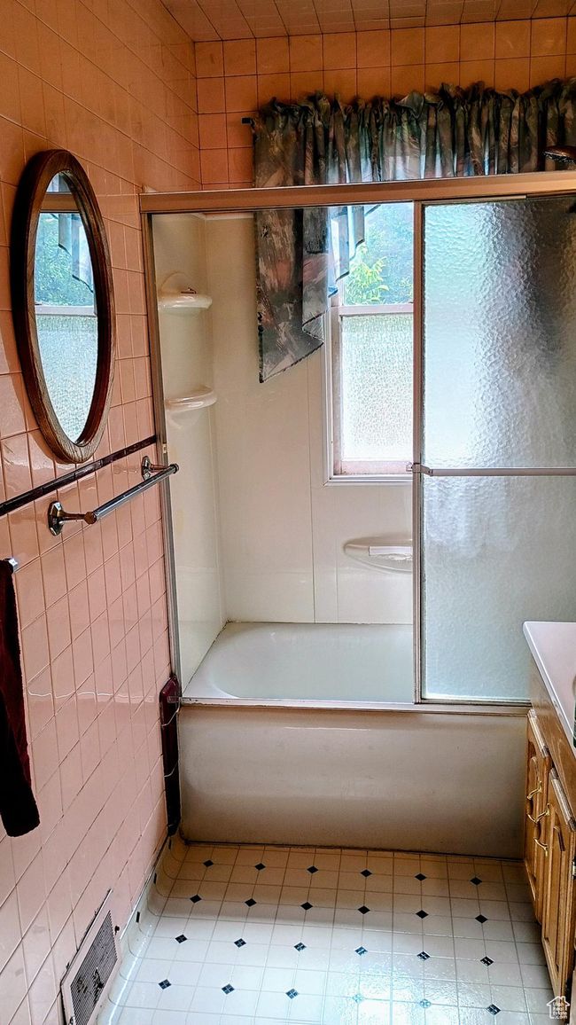 Full bath with combined bath / shower with glass door, plenty of natural light, vanity, and tile walls | Image 35