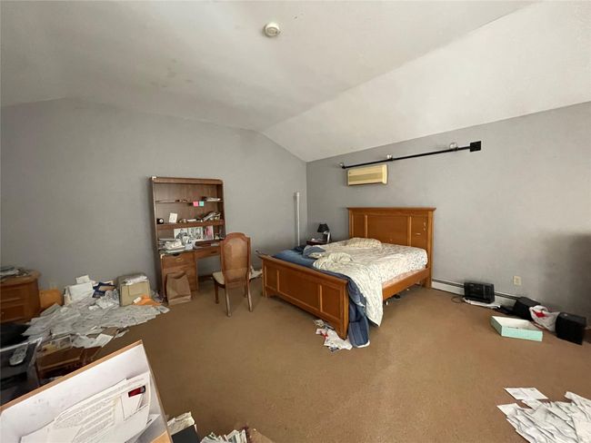 Carpeted bedroom with an AC wall unit, a baseboard radiator, and lofted ceiling | Image 8