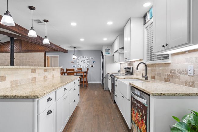 Kitchen with appliances with stainless steel finishes, tasteful backsplash, white cabinets, light stone countertops, and recessed lighting | Image 11