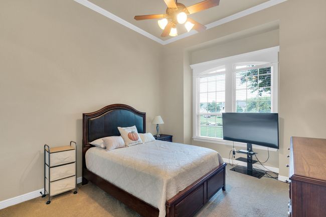 Bedroom featuring light colored carpet, ornamental molding, and a ceiling fan | Image 27