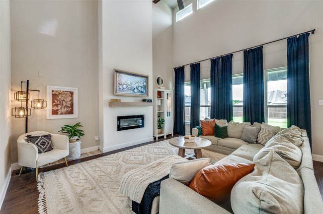 Living area featuring baseboards, a towering ceiling, a glass covered fireplace, and wood finished floors | Image 9