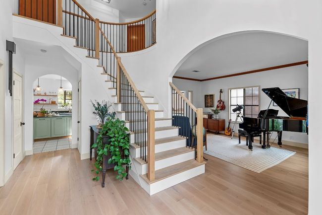 Stairway featuring arched walkways, plenty of natural light, wood finished floors, and crown molding | Image 6