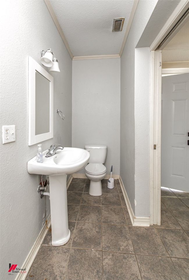 Bathroom with a textured ceiling, visible vents, crown molding, baseboards, and toilet | Image 21