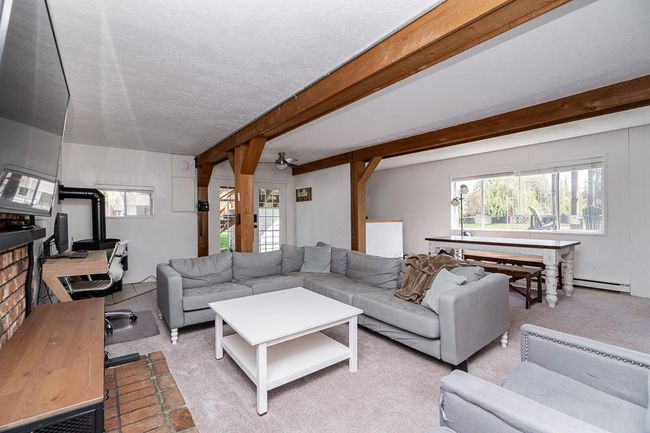 Carpeted living room with beam ceiling, a baseboard radiator, and ceiling fan | Image 33
