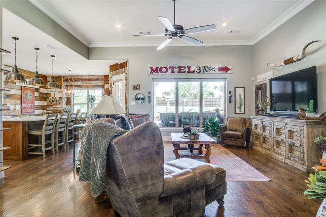 Living room with a ceiling fan, dark wood-style flooring, crown molding, and visible vents | Image 7