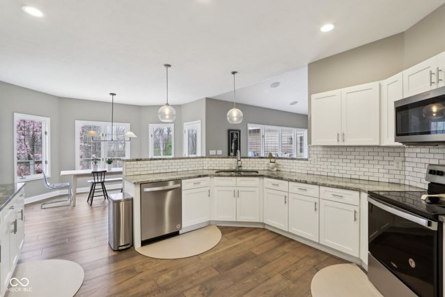 kitchen featuring white cabinetry, tasteful backsplash, stainless steel appliances, a sink, and dark wood-style floors | Image 14