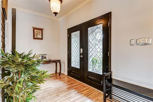 Bathed in natural light from the glass-paneled doors, this welcoming entryway sets the tone for the home’s refined aesthetic. Gleaming floors, soft neutral hues, and a flush-mount fixture add warmth and elegance to this first impression. | Image 5