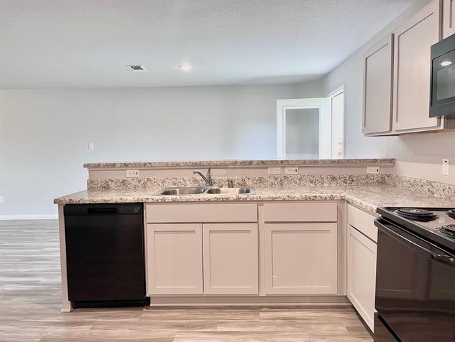 Modern kitchen with sleek countertops, ample cabinetry, and bright lighting—perfect for culinary creativity. Virtually staged for inspiration. | Image 22