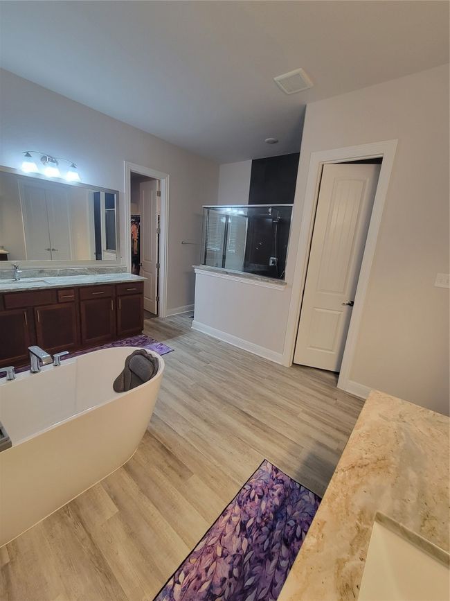 Bathroom with a shower stall, wood finished floors, vanity, baseboards, and a soaking tub | Image 4