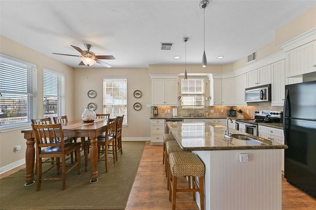 Spacious eat-in kitchen featuring granite countertops and drop-down lighting over the island. | Image 9