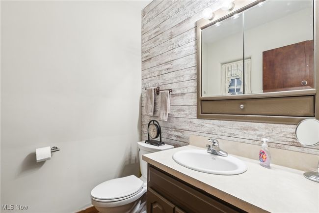Half bath with wooden walls, vanity, and toilet | Image 16