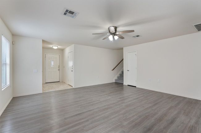Unfurnished living room with stairs, ceiling fan, light wood finished floors, and baseboards | Image 10
