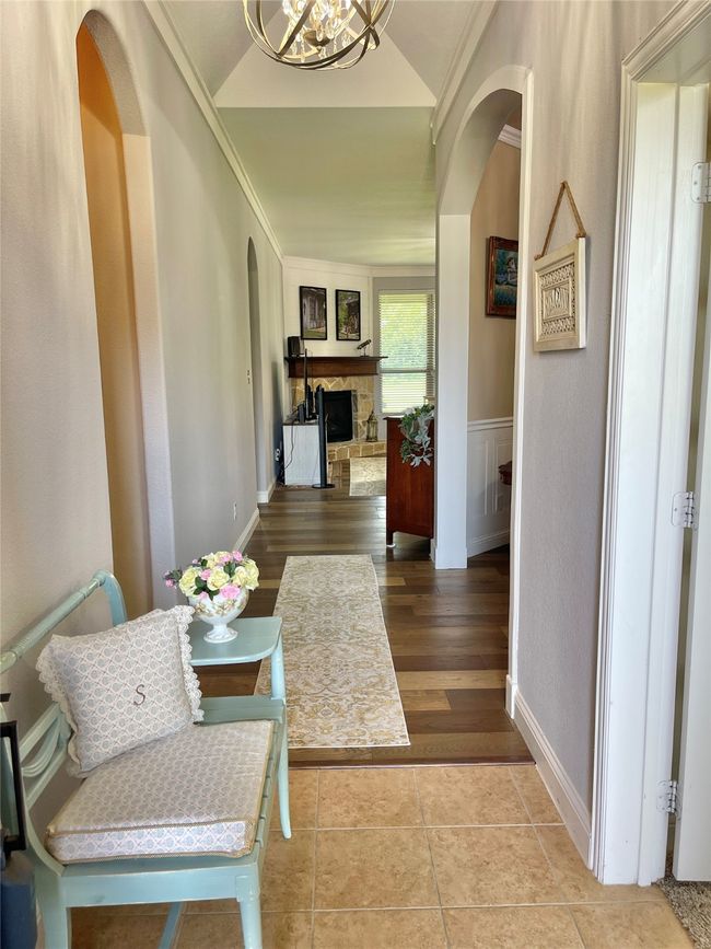 Corridor with arched walkways, lofted ceiling, a chandelier, and crown molding | Image 7