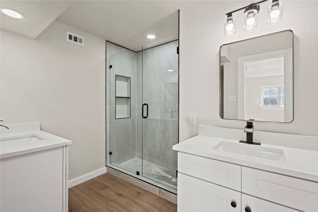 Full bath with a marble finish shower, two vanities, a sink, and wood finished floors | Image 20