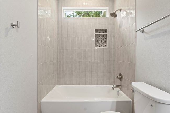A gorgeous, spacious bathroom with a sleek vanity, a bath-shower combo, and brilliant natural light. | Image 28