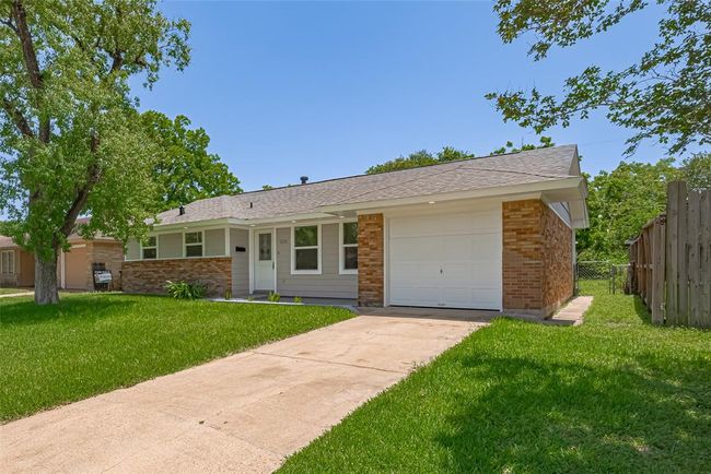 The front view of the home features the attached garage and paved driveway, framed by fresh landscaping. | Image 32
