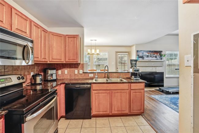 Kitchen featuring appliances with stainless steel finishes, a chandelier, a peninsula, backsplash, and open floor plan | Image 15