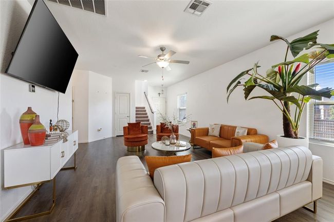 Living area with dark wood-type flooring, stairway, a ceiling fan, and baseboards | Image 5