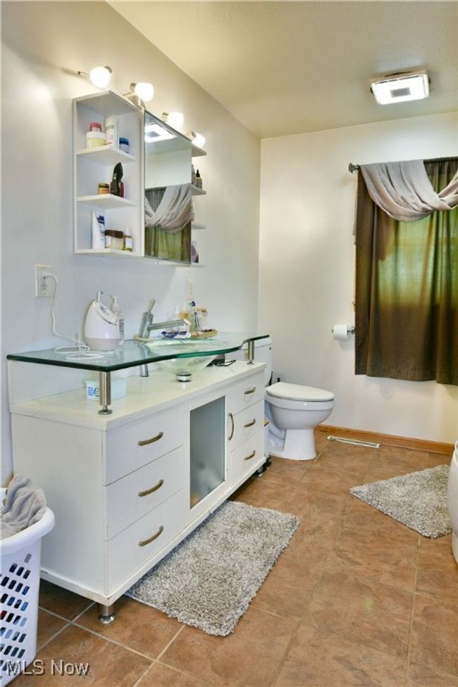 Bathroom with toilet, vanity, tile patterned flooring, and baseboards | Image 23