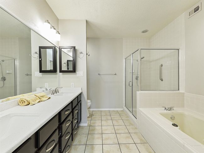 Bathroom featuring tile patterned floors, visible vents, a shower stall, and a sink | Image 15