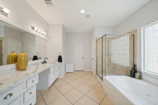 The ensuite bathroom boasts a long double-sink vanity with marble-look counters and plenty of storage to keep everything organized. | Image 27